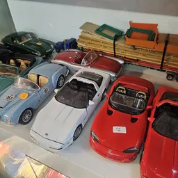 Verzameling speelgoedauto's en vrachtwagens uitgestald op een witte plank