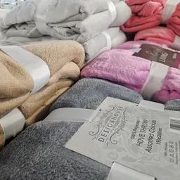 Verschillende gekleurde handdoeken en badhanddoeken netjes opgerold en uitgestald met prijskaartjes.