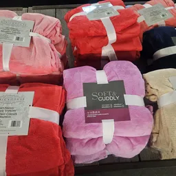 Uitgestalde fleece deken en dekens in verschillende kleuren op een tafel in de winkel