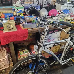 Tafel met diverse tweedehands spullen: boeken, fietsen, helmen, speelgoed en huishoudelijke artikelen