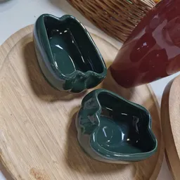 Twee donkergroene keramische schalen met organische vormen op houten tafel