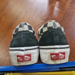 Twee tweedehands Vans sneakers met zwart-wit ruitpatroon op houten ondergrond