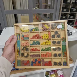 Houten sorteerkast met gekleurde kralen, houten kralen en andere hobbymateriaal in verschillende vakjes