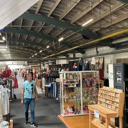 Winkelvloer van kringloopwinkel met kleding aan rekken, display kasten met accessoires en diverse tweedehands artikelen