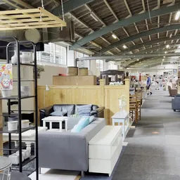Winkelvloer met uitgestalde meubels, bedden en andere tweedehands artikelen in een grote kringloopwinkel