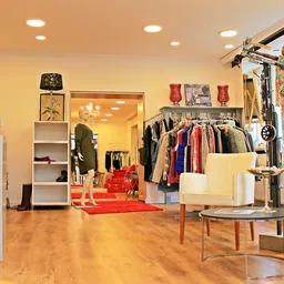 Winkelvloer met kledingrekken, spiegels en displaymeubels in een verlichte designerwinkel