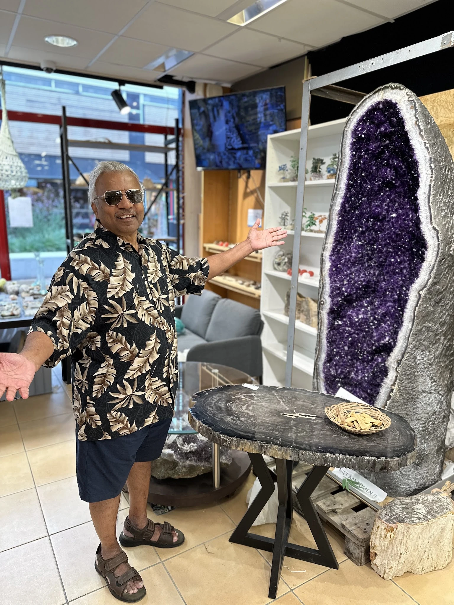 Man toont grote paarse amethist geode met witte kristallijne rand naast zwarte steen