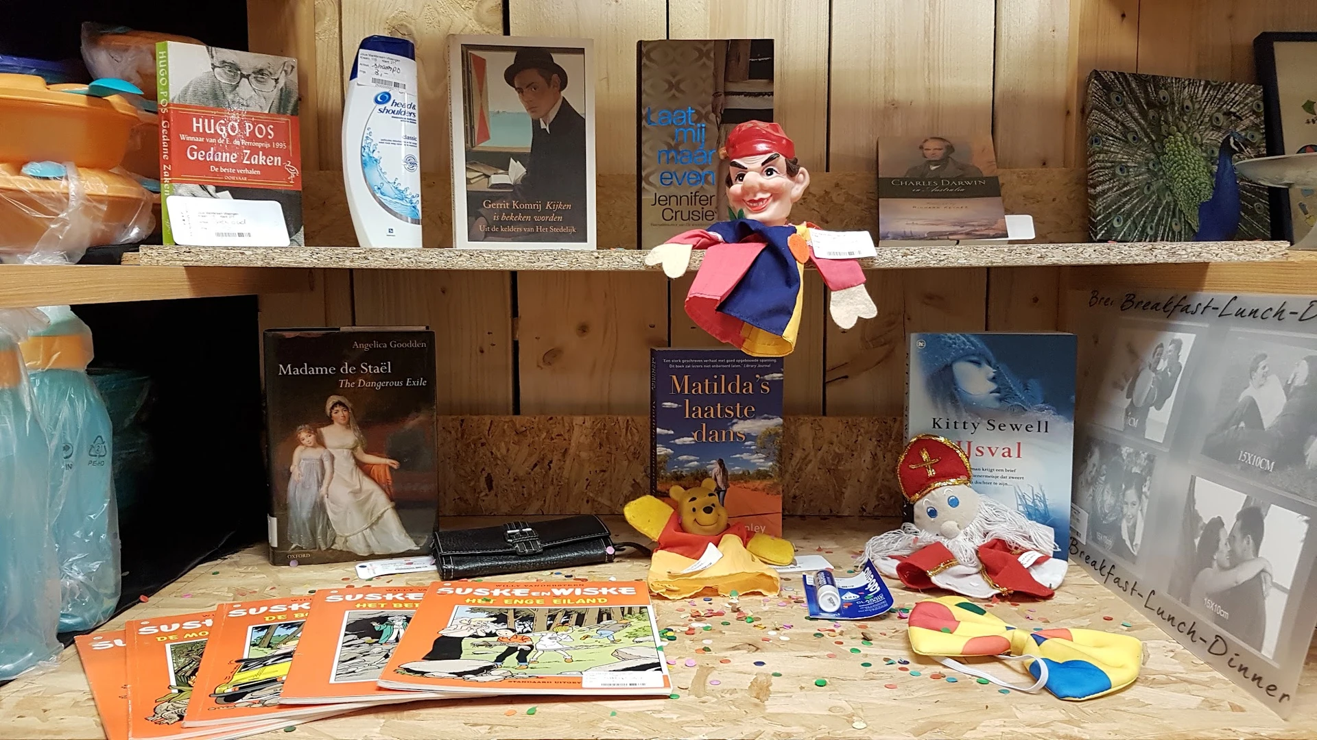 Verschillende tweedehandsartikelen uitgestald op een tafel: boeken, speelgoed, kinderspullen en andere voorwerpen