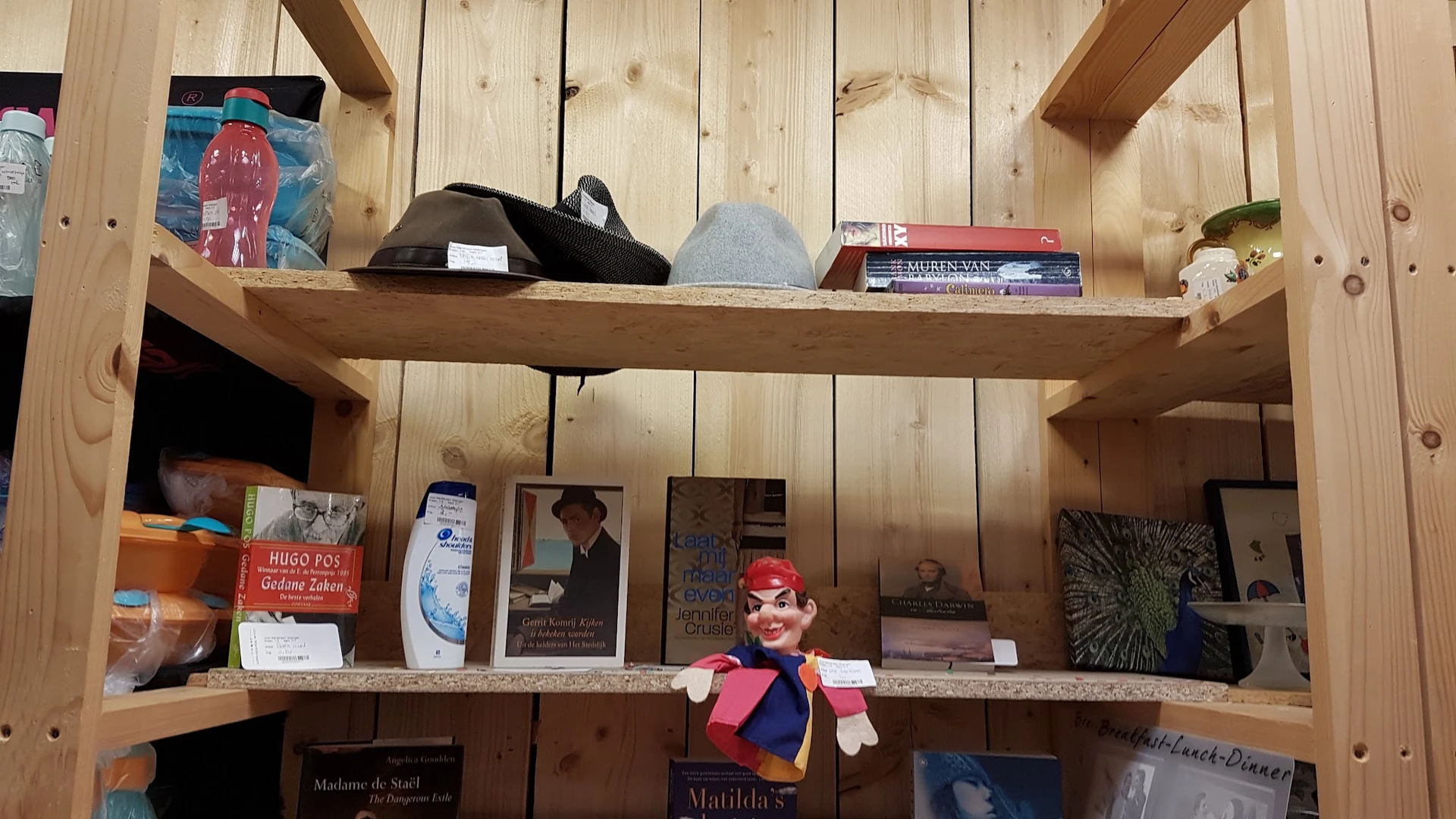Houten stellingen met boeken, mineralen, beeldjes en diverse tweedehandsspullen uitgestald