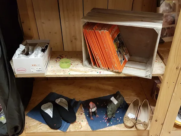Houten kast met verschillende spullen: dozen, boeken, schoenen en diversen op twee schappen