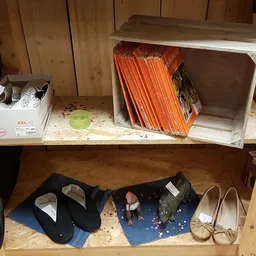 Houten kast met verschillende spullen: dozen, boeken, schoenen en diversen op twee schappen