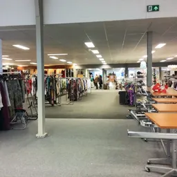 Overzicht van de winkelvloer met kledingrekken, toonbanken en diverse spullen uitgestald