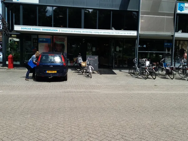 Voorgevel van kringloopwinkel met etalage, parkeerplaats met auto en fietsenrek