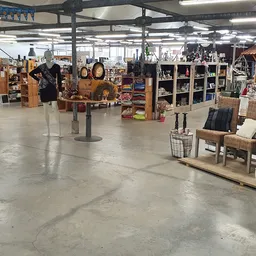 Ruim winkelinterieur met houten meubels, stellingen, decoratieve items en kleding op hangrekken
