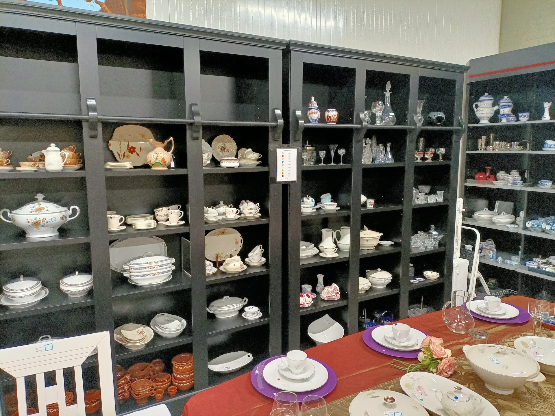Glazen vitrinekast met serviesgoed, bordenwaar en decoratieve items uitgezocht naar waarde