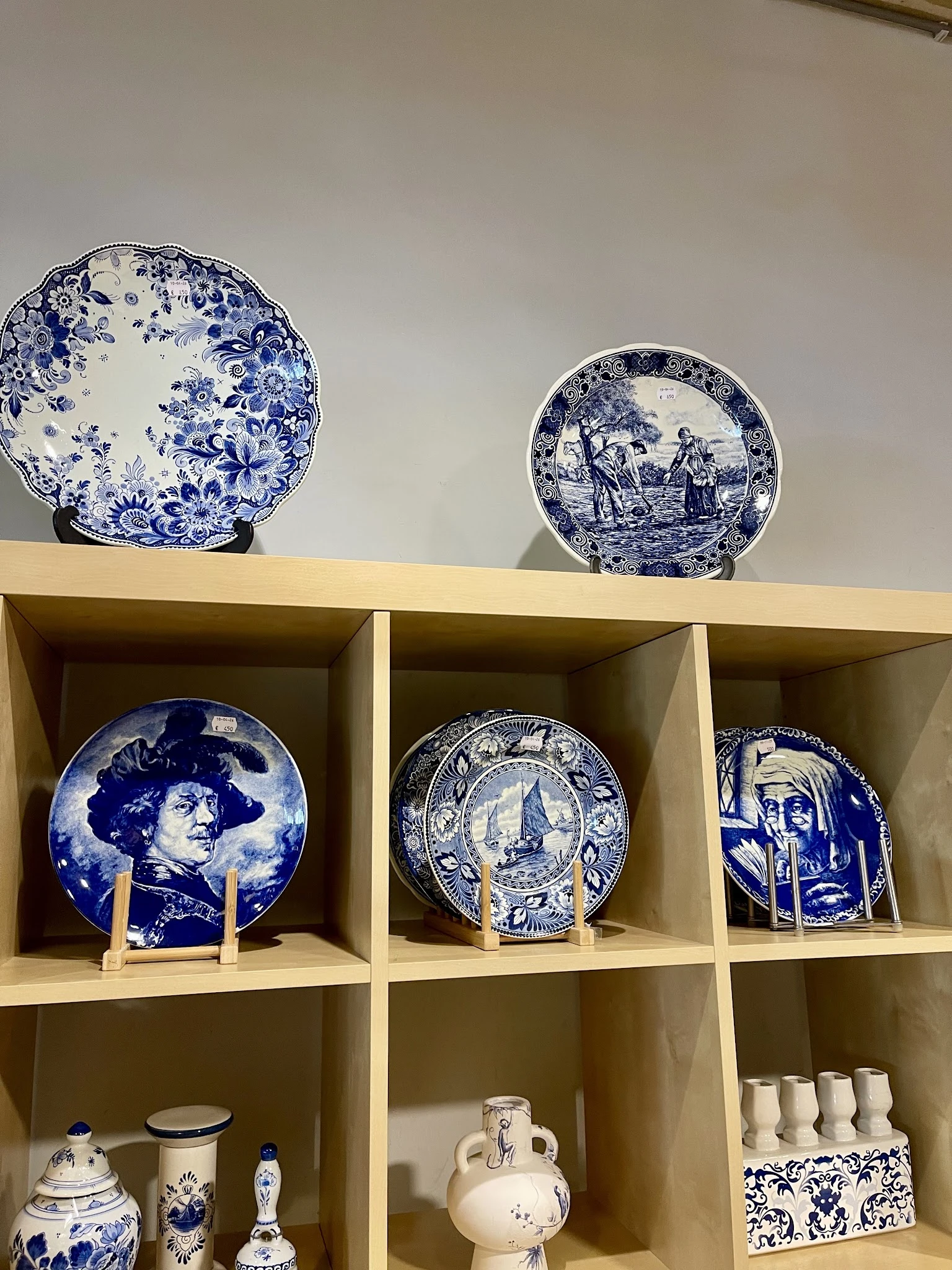 Glazen schappen met blauw-wit aardewerk bordjes en decoratieve servieswerk uitgestald