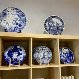 Glazen schappen met blauw-wit aardewerk bordjes en decoratieve servieswerk uitgestald
