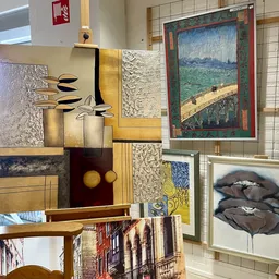 Diverse kunstwerken en decoratiestukken waaronder schilderijen, prints, vazen en sculpturen op stellingen uitgestald