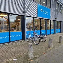 Blauwe gevel van Dorcas kringloopwinkel met grote ramen, twee fietsen geparkeerd ervoor