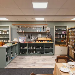 Winkelinterieur met grijze kasten, houten planken, huishoudelijke artikelen en serviesgoed uitgestald