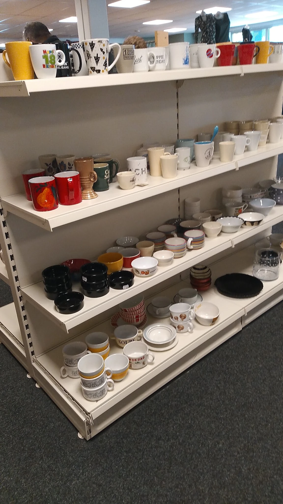 Stellingen met keramiek, servies, mokken en huishoudartikelen in een kringloopwinkel