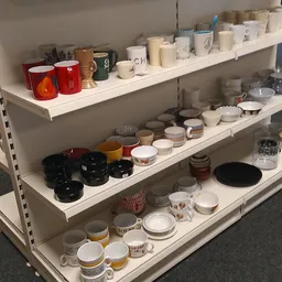Stellingen met keramiek, servies, mokken en huishoudartikelen in een kringloopwinkel