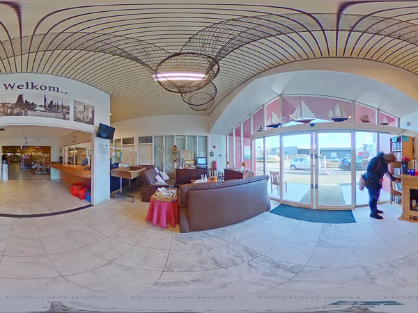 Ingang en ontvangsthal van kringloopwinkel met loungezetel, informatiedisplay en grote ramen