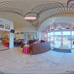 Ingang en ontvangsthal van kringloopwinkel met loungezetel, informatiedisplay en grote ramen