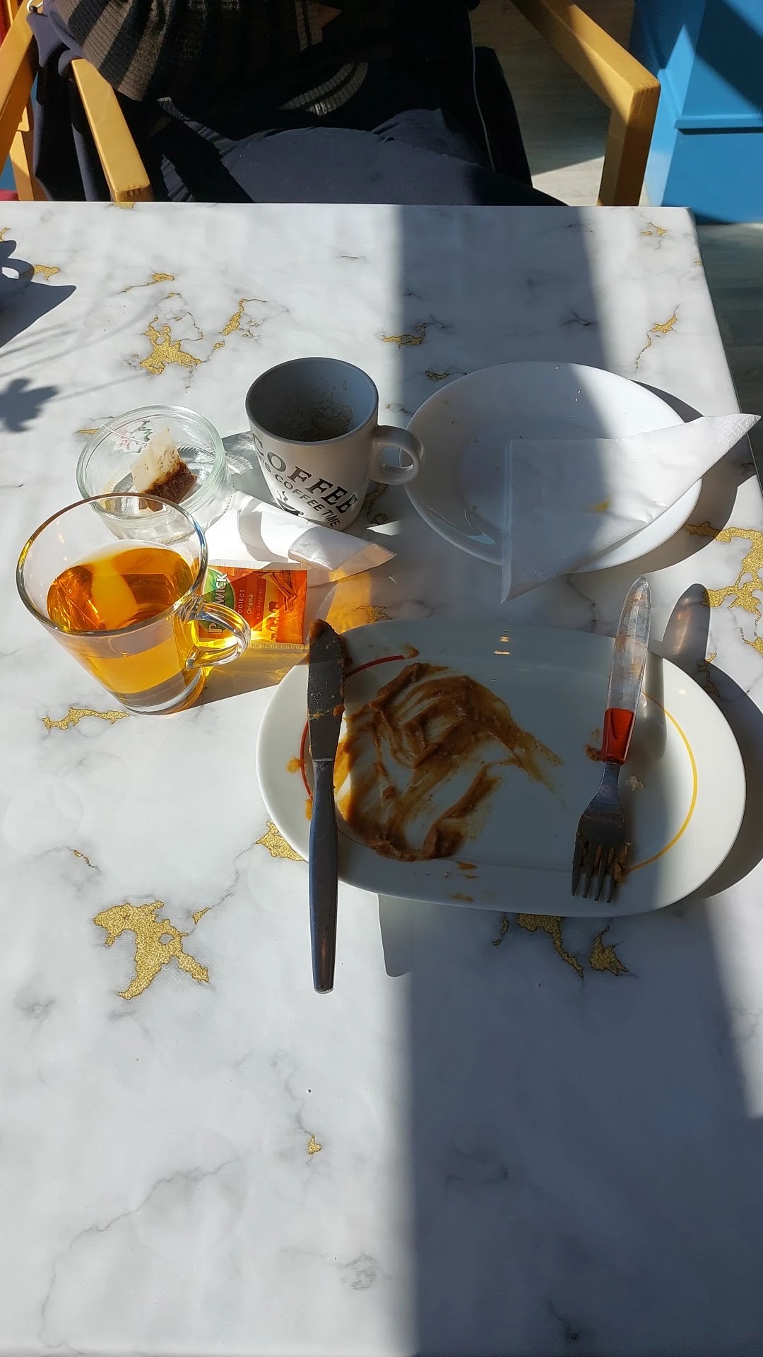 Bord met eten en glas thee op een terras met marmeren tafel