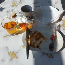 Bord met eten en glas thee op een terras met marmeren tafel