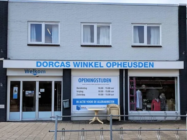 Gevel van Dorcas Winkel Opheusden met witte gevelbekleding, drie ramen, openingstijden en welkomstbord