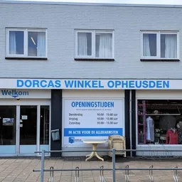 Gevel van Dorcas Winkel Opheusden met witte gevelbekleding, drie ramen, openingstijden en welkomstbord