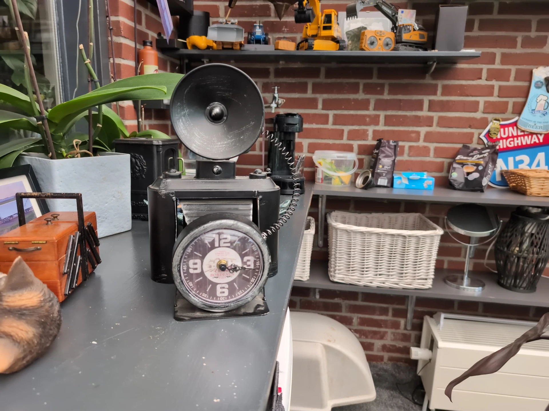 Vintage zwarte telefoon met draaistelsel en klok in voorkant, klokradio op grijze tafel