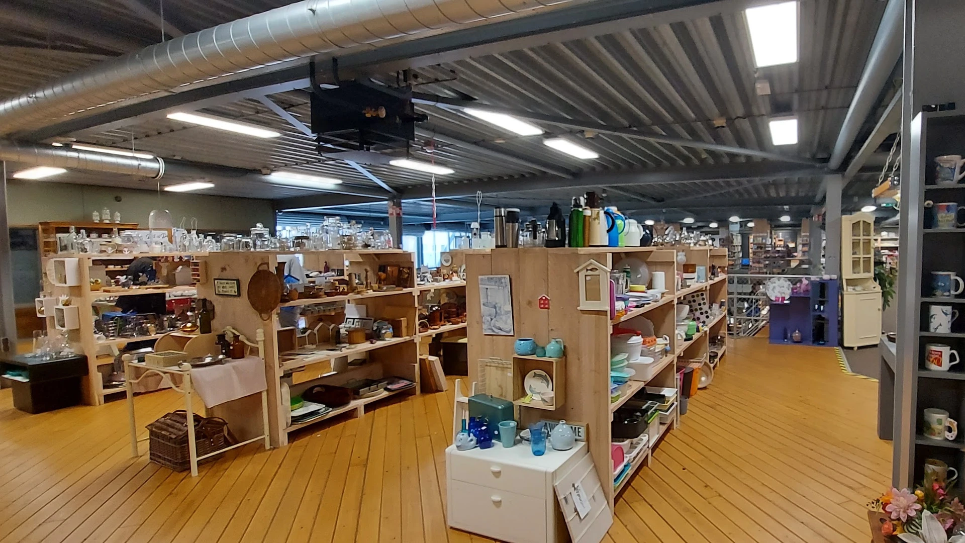 Winkelvloer met houten stellingen vol tweede-handsspullen en diverse huishoudartikelen