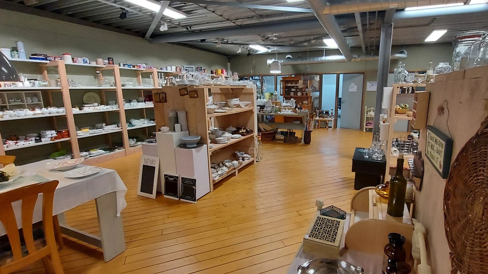Winkelvloer met houten planken, stellingen met diverse spullen en artikelen, overhead verlichting en industrieel plafond