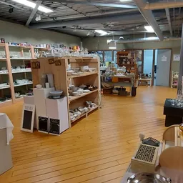 Winkelvloer met houten planken, stellingen met diverse spullen en artikelen, overhead verlichting en industrieel plafond