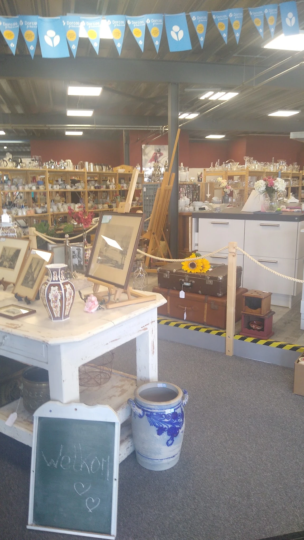 Verzameling van tweedehands huishoudartikelen, decoraties en meubels uitgestald in de kringloopwinkel, met onder meer vazen, 