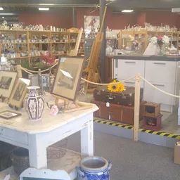Verzameling van tweedehands huishoudartikelen, decoraties en meubels uitgestald in de kringloopwinkel, met onder meer vazen, 