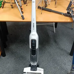Bosch elektrische bezem met 25,2V accu, staand gepositioneerd tegen tafels