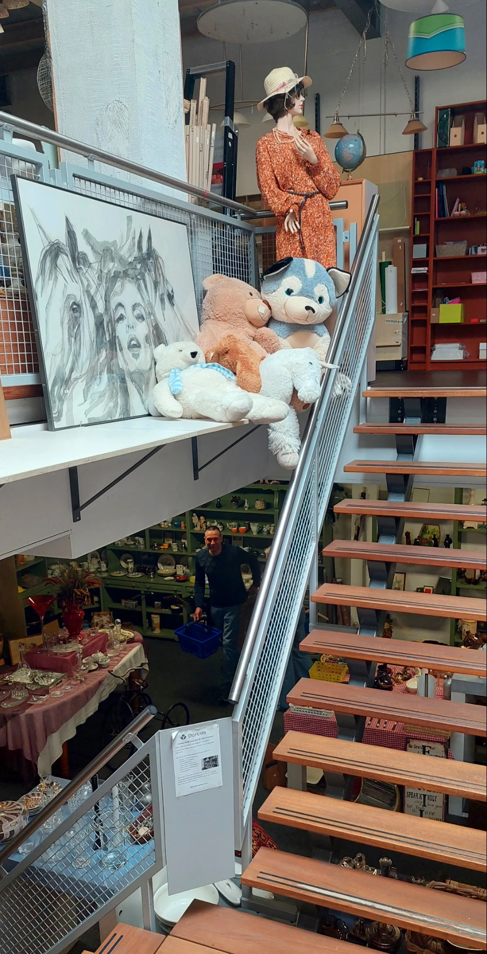 Overzicht van winkelinterieur met trap, stellingen met spullen en knuffeldieren op bovenkant