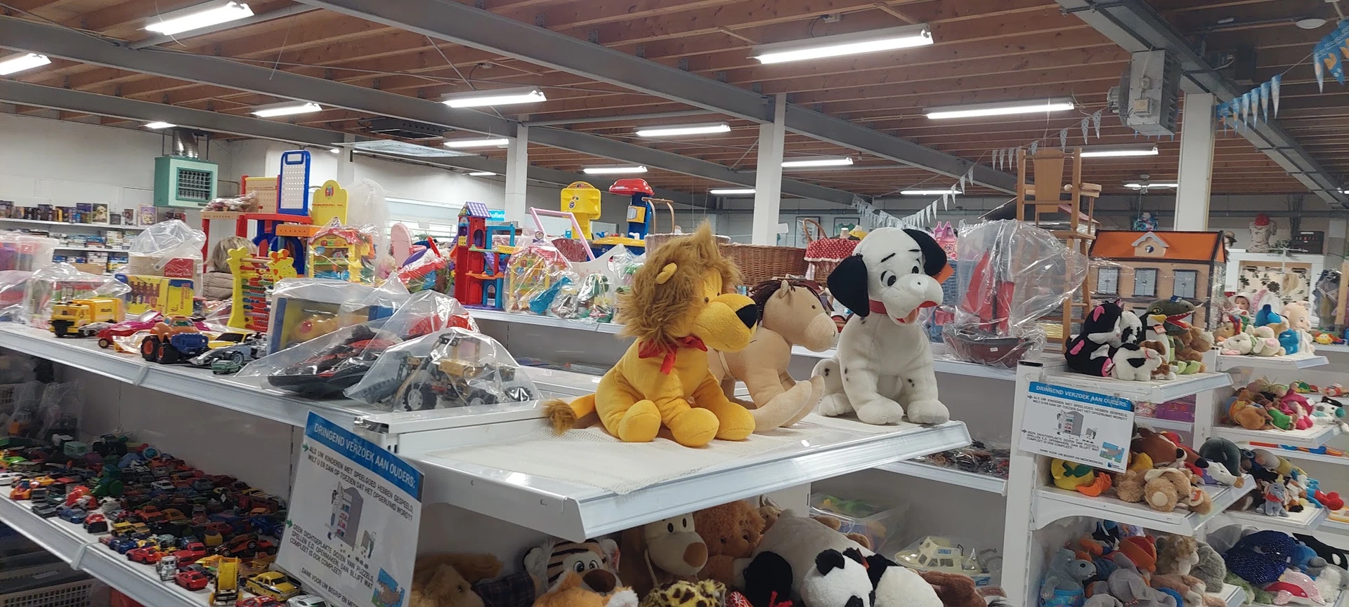 Uitgestalde pluchen knuffeldieren en speelgoed op een winkelrek in een kringloopwinkel