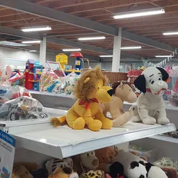 Uitgestalde pluchen knuffeldieren en speelgoed op een winkelrek in een kringloopwinkel
