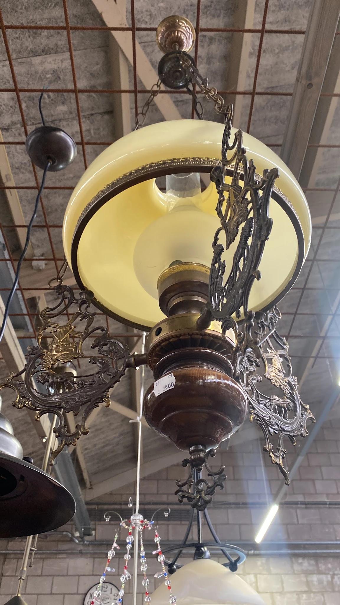 Vintage hanglamp met gele glazen kap en donkerbruin metalen voet met decoratief ornament