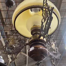 Vintage hanglamp met gele glazen kap en donkerbruin metalen voet met decoratief ornament