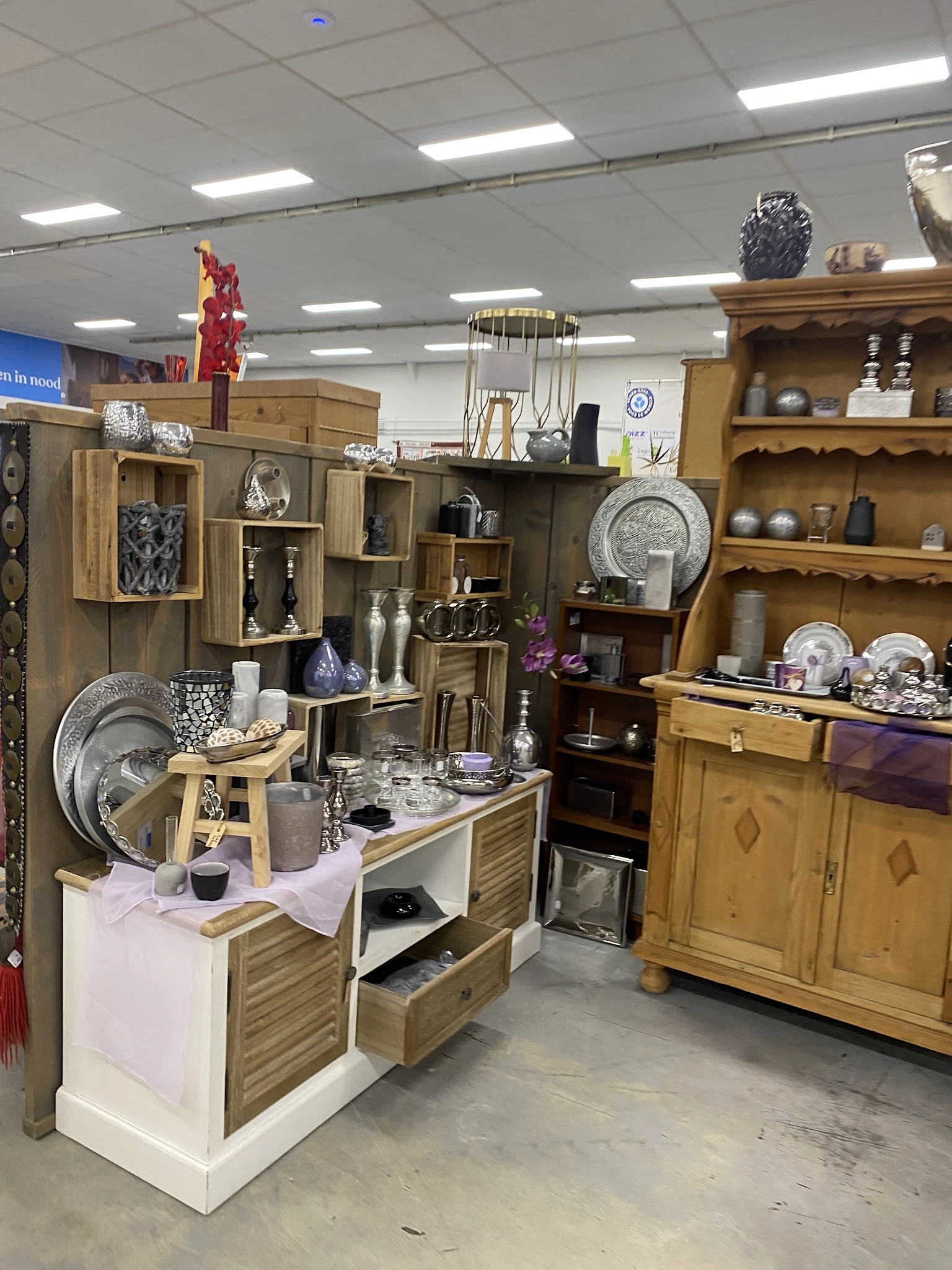 Uitgestalde huishoudelijke artikelen, servies, decoratie en meubelstukken in de kringloopwinkel