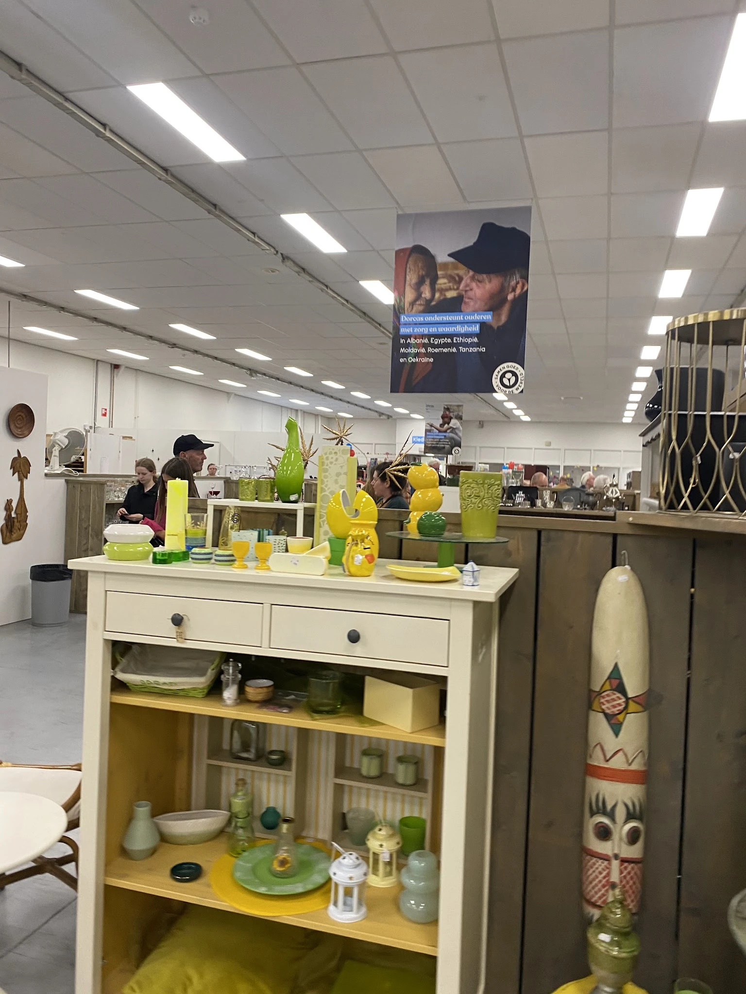 Witte kast met gele en groene huishoudelijke artikelen en decoratieve voorwerpen op de toonbank