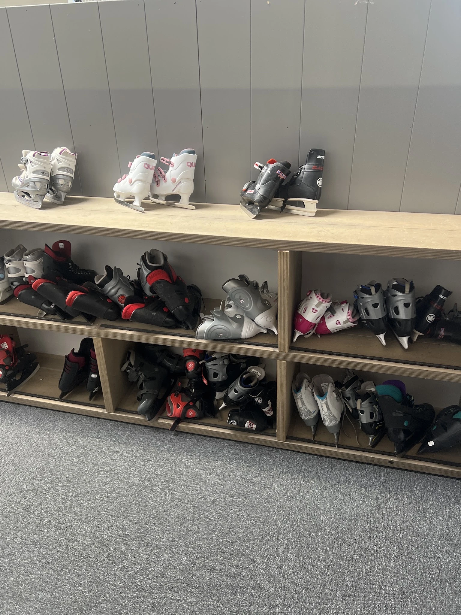 Stellingen met uitgestalde rolschaatsen en beschermingsuitrusting in verschillende kleuren en maten