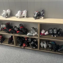 Stellingen met uitgestalde rolschaatsen en beschermingsuitrusting in verschillende kleuren en maten