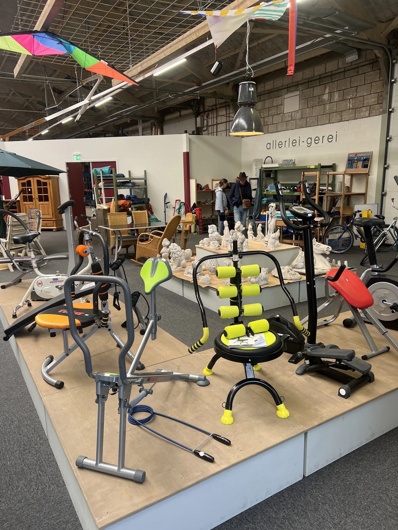 Tweedehands sportapparatuur en fitnesstoestellen uitgestald in de winkel, waaronder hometrainers, halters en andere trainings