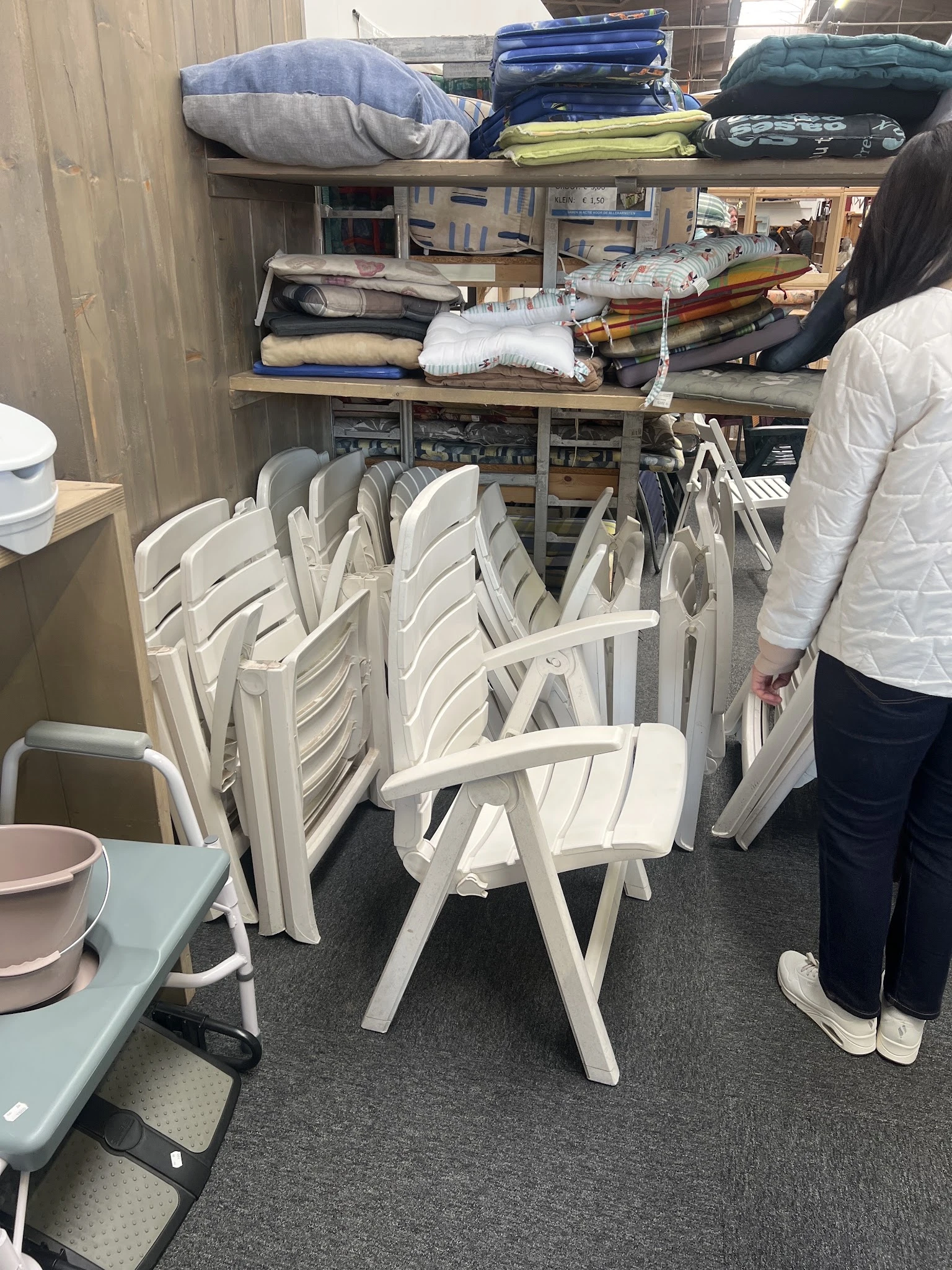 Stapel witte kunststof stoelen in een kringloopwinkel, opgevouwen voor opslag